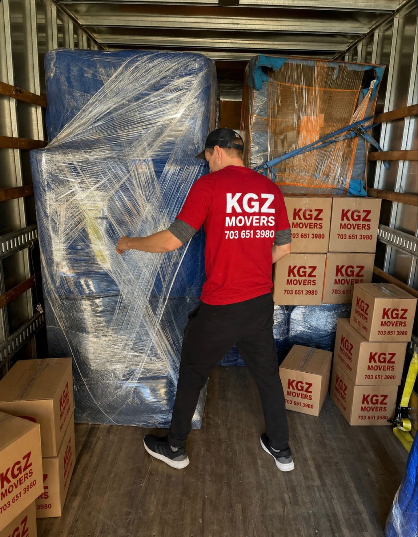 KGZ Movers crew securing wrapped furniture inside a truck